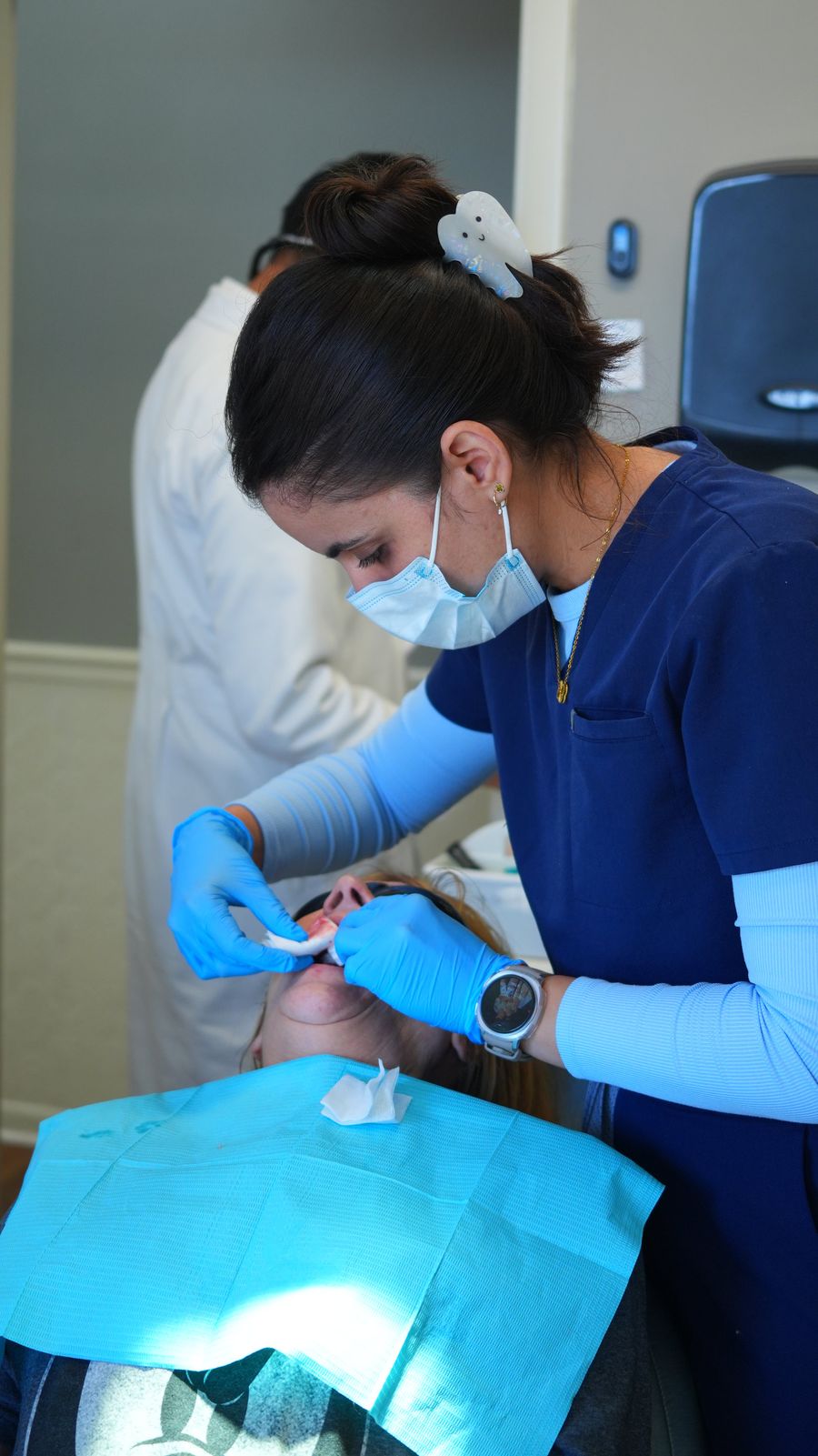 A Franklin Dental hygienist in navy scrubs treating a patient