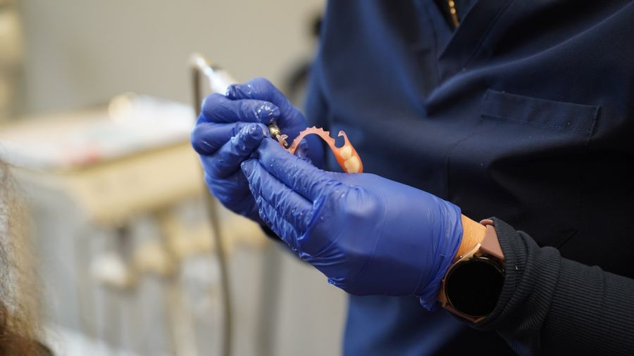 Gloved hands holding a partial denture